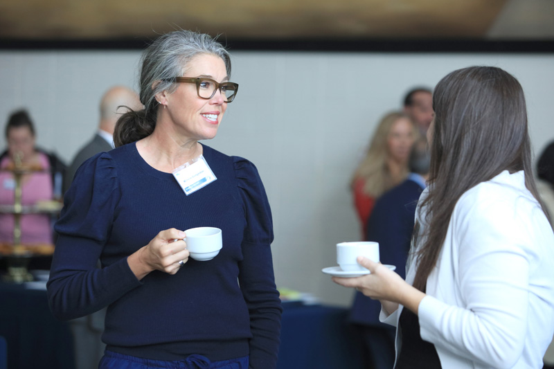 two attendees talking, drinking coffee.