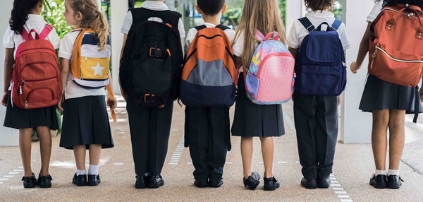 Seven kids in a line wearing backpacks