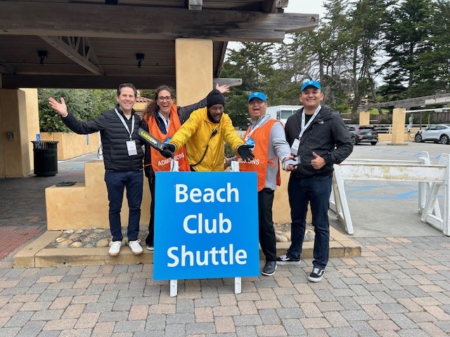Volunteers and security in front of a sign that says Beach Club Shuttle