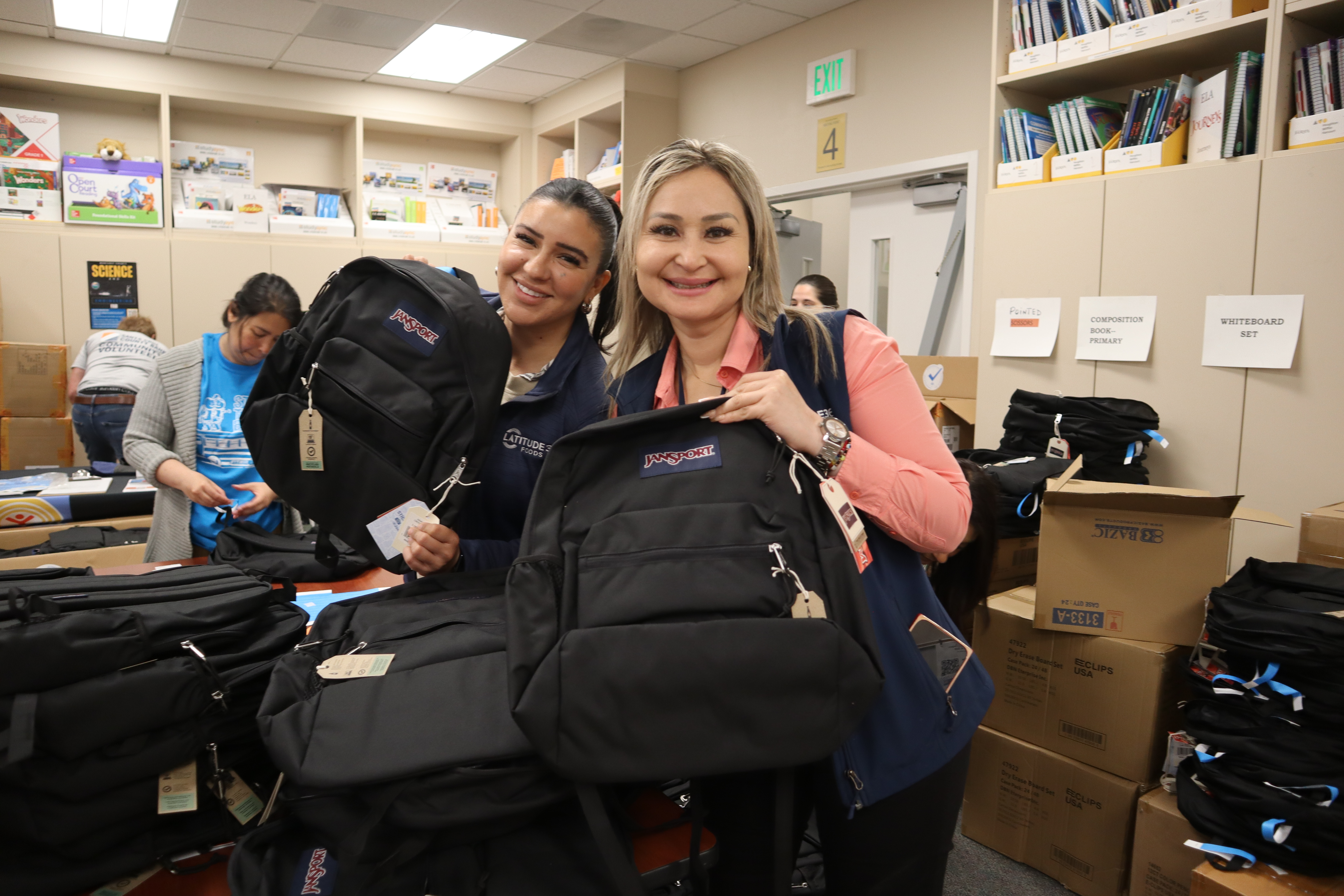 Two volunteers holding up backpacks