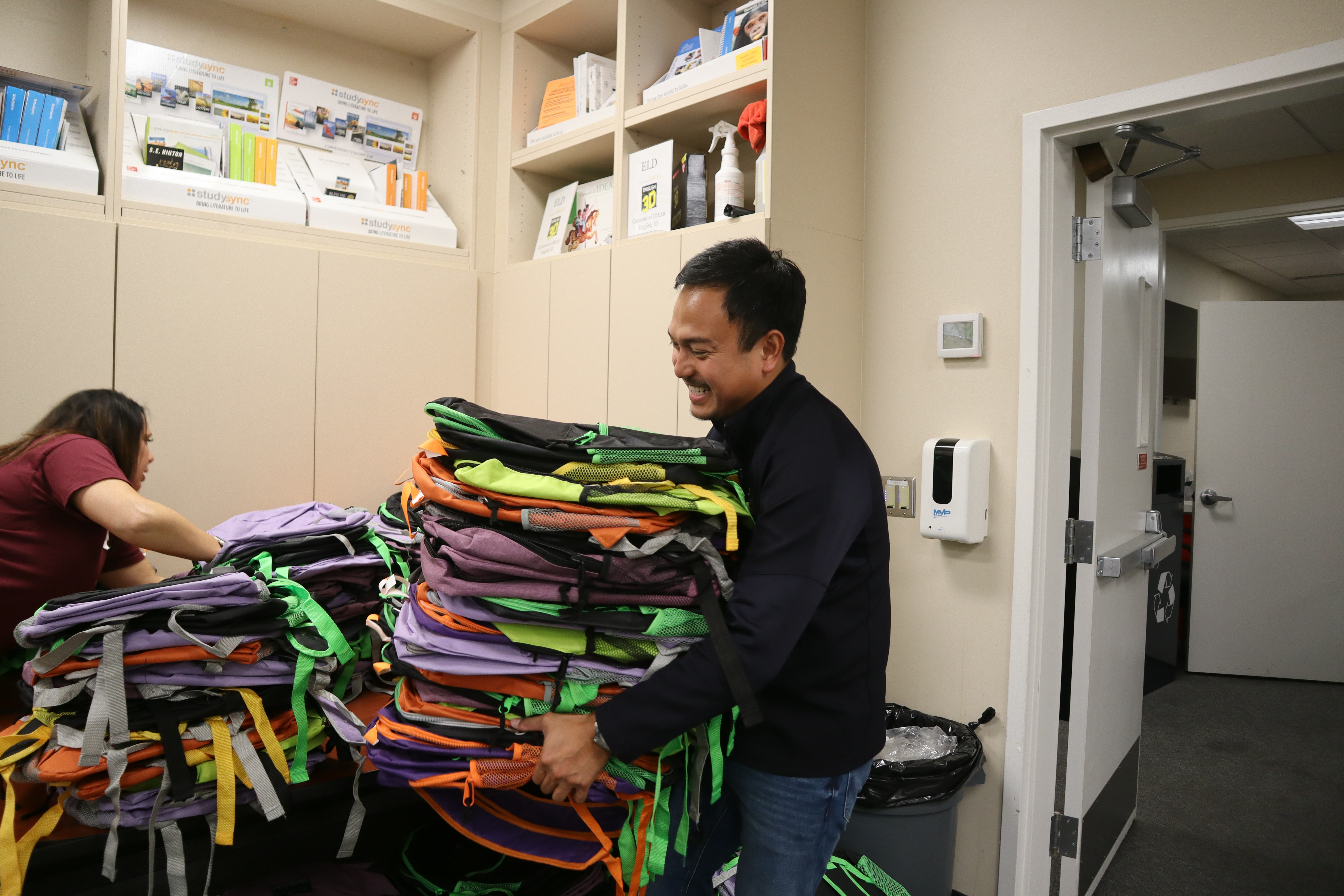 Volunteer carrying a stack of backpacks