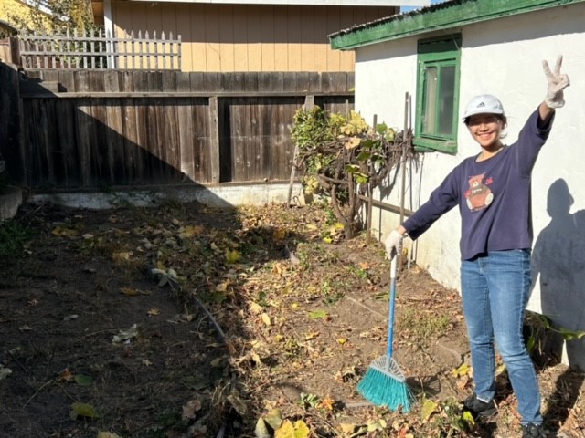 Person holding a broom and a peace sign